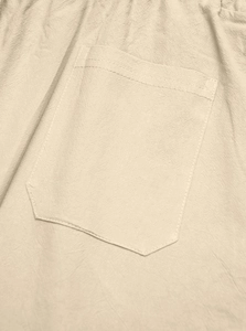 Macro detail of beige linen trousers showing rear pocket stitching and fabric texture