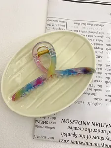 Macro detail of a 13cm rainbow gradient acrylic claw clip on a wavy cream tray