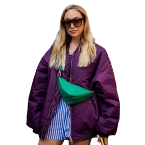 Women oversized purple bomber jacket styled with green triangle crossbody bag and sunglasses