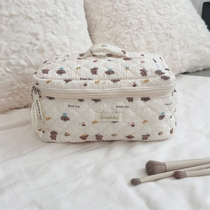 Close-up of quilted cosmetic bag featuring cute bear print and sturdy top handle