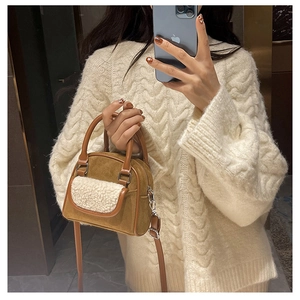 Close-up of brown suede handbag with white faux shearling pocket and knitted sweater