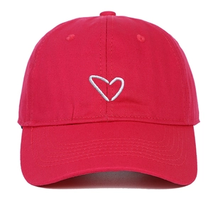 Close-up of a red cotton baseball cap with a white embroidered heart on the curved brim