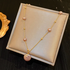 Detail of gold chain necklace with pink-purple baroque freshwater pearls in a gift box