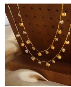 Macro shot of gold shell pendant with zircon inlays on a beige satin fabric