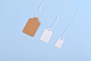Three kraft and white paper price tags with strings for jewelry and glasses