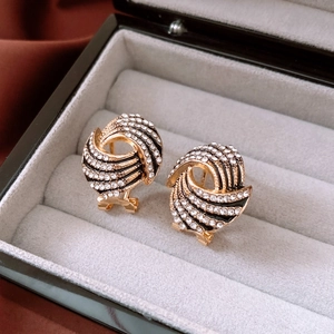 Macro shot of gold-plated twisted wing earrings with sparkling crystals in a jewelry box