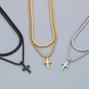 Detailed shot of double-layer Cuban link necklaces with cross pendants in black, gold, and silver