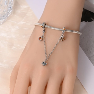 Macro shot of silver maple leaf safety chain charm with orange gemstones on a bracelet