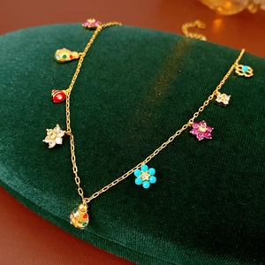 Detailed close-up of golden necklace with colorful ladybug and flower charms on velvet