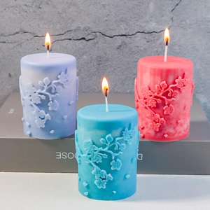 Detail beleuchteter Zylinderkerzen mit Blumenprägung in Lila, Blau und Rosa Farben
