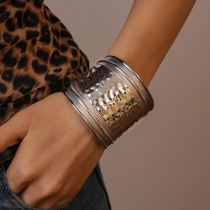 Close-up of a wide silver cuff bracelet with hammered texture and intricate bead borders
