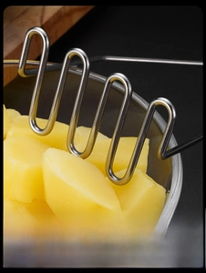 Vue macro du presse-purée ondulé en acier inoxydable écrasant des pommes de terre