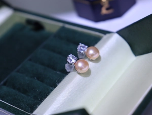 Detailed macro shot of freshwater pearl earrings with zircon inlay in a velvet box