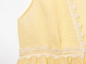 Detail of light yellow top featuring delicate white lace trim and high-quality fabric texture