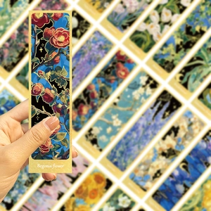 Handheld detail of artistic Begonia flower bookmark with gold lines on blue background