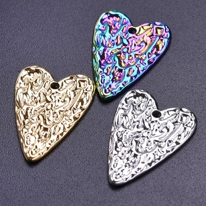 Close-up of three hammered heart pendants in gold, silver, and rainbow steel