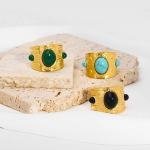Detailed close-up of bohemian gold rings with turquoise and malachite stones on stone base