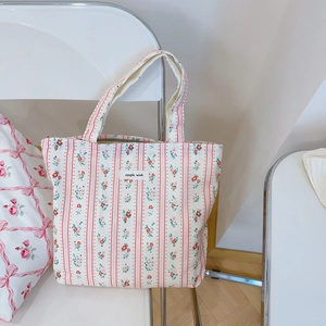 Sac fourre-tout en coton fleuri avec rayures rouges accroché à une chaise blanche