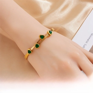 Detailed shot of a gold-plated titanium steel bracelet with four green zircon hearts