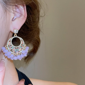Detail of crystal fringe earrings with purple beads and sparkling geometric hoop on ear