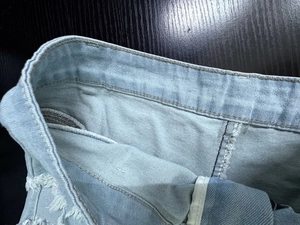 Dettaglio della trama del denim celeste e delle cuciture in vita sui pantaloncini estivi