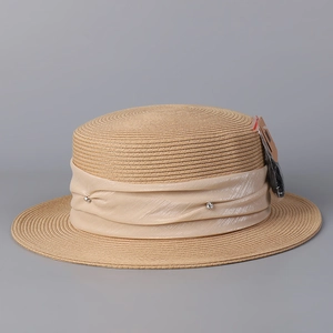 Détail du ruban en soie champagne avec strass sur un chapeau de paille beige