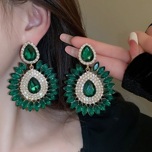 Detailed view of model wearing large emerald green teardrop crystal floral drop earrings