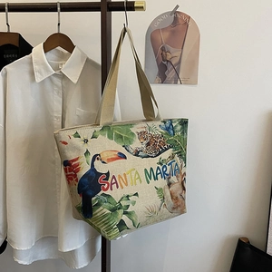 Detailed close-up of a beige tropical linen tote bag featuring leopard and toucan prints
