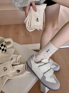 Gros plan détaillé de chaussettes en maille beige avec broderie chiot et mouchetures
