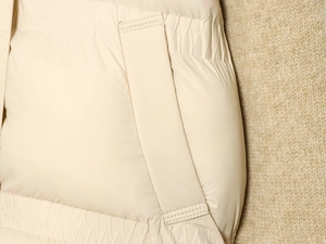 Detailed close-up of cream quilted jacket with side pocket and elastic hem texture