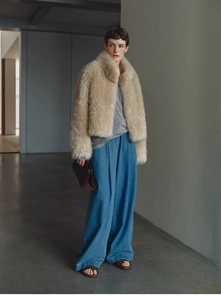 Faux fox fur vest with high collar paired with wide leg jeans in a modern interior