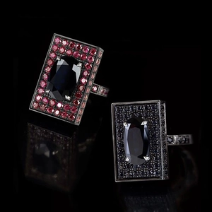 Macro shot of two wide square rings with deep blue and dark stones on black background