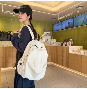 Detail of white pleated backpack featuring black zippers and side drawstring pockets