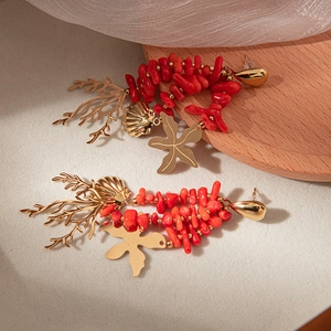 Close-up of golden coral sea life drop earrings with red beads and starfish charms
