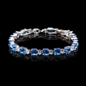 Detail of silver bracelet with square blue and round white zircons on black surface