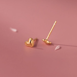 Elegant s925 silver heart stud earrings in gold with beaded edges on a soft pink background