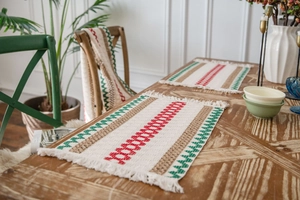 Detailed close-up of woven Christmas placemat with red and green stripes and fringe trim
