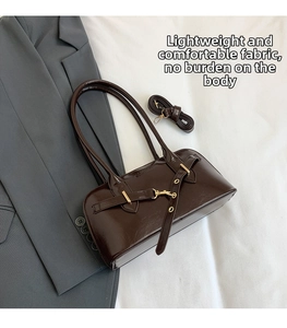 Close-up of vintage dark brown patent leather bowling bag with gold hardware on white linen
