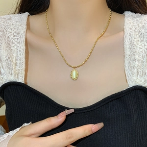 Vintage gold necklace with oval opal pendant and braided frame worn on neck