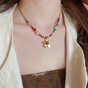 Detail of bohemian necklace with multi-color beads and gold flower charm on model