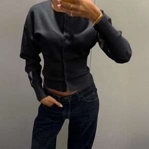 Gros plan d'un gilet en tricot noir avec poignets côtelés et une silhouette décontractée