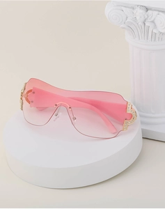 Close-up of pink gradient Y2K sunglasses with rhinestone-embellished gold metal hinges