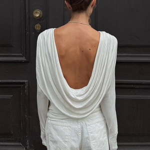 Detail showing the white long sleeve top with an elegant open back and draped pleats