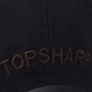 Macro detail of high-quality brown 3D embroidery on a black washed cotton baseball cap