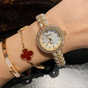 Close-up of elegant gold watch with pearl bracelet and diamond accents on a model wrist