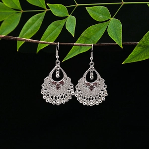 Detail of ethnic silver alloy earrings with red enamel and dangling bell tassels