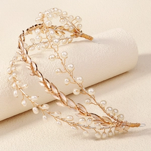 Close-up of golden bridal hair vine with delicate leaf design and white pearls