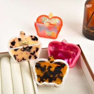 Set of 4 acetate apple hair claws in leopard print and marble pink on a velvet tray