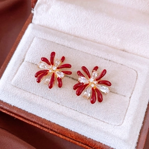 Detailed macro view of 18k gold flower earrings with red enamel and sparkling zircons