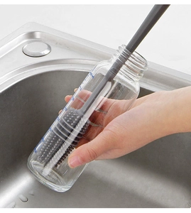 Dettaglio dello scovolino grigio in silicone che pulisce l'interno di una bottiglia di vetro